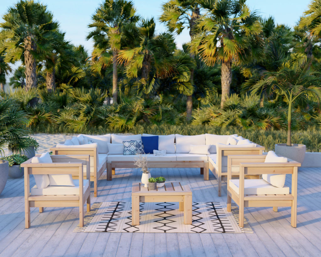 White-cushioned DIY U-shaped outdoor sectional made of 2x4 lumber on a beachside patio, with ocean view in the background