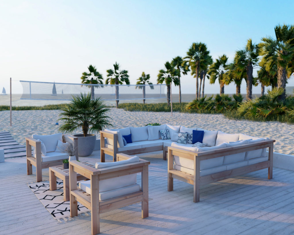 White-cushioned DIY U-shaped outdoor sectional made of 2x4 lumber on a beachside patio, with ocean view in the background