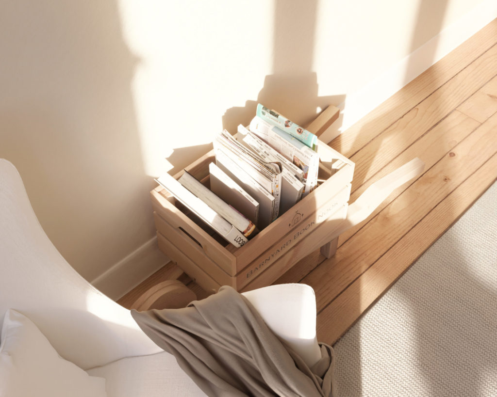 A rustic wooden wheelbarrow holding magazines and books, placed next to a cozy reading chair in a living room.