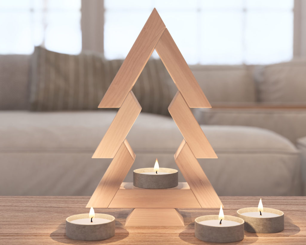 Handcrafted wooden Christmas tree decor on a tabletop with tealight candles illuminating its base.