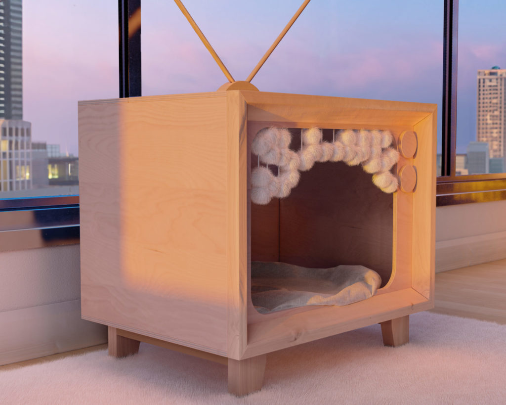 Cat resting in a wooden vintage television-shaped house with antenna and control dials, placed by a window with cityscape view.