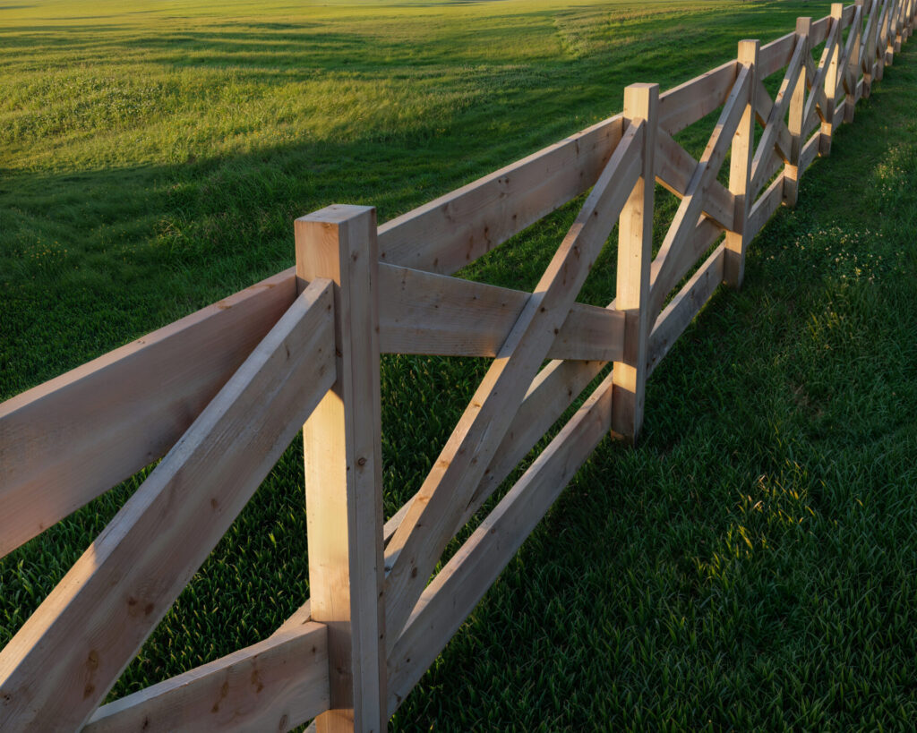 DIY crossbuck wooden fence surrounding a green pasture