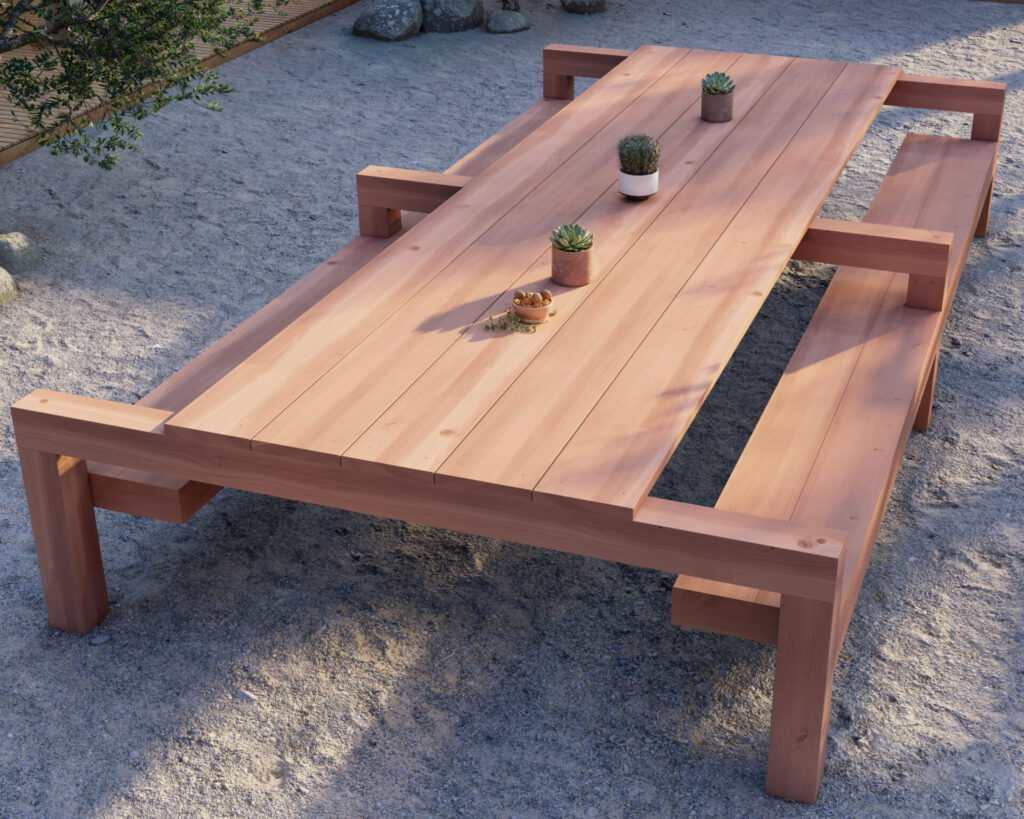 Sturdy outdoor redwood table and bench set positioned on gravel with green potted plants on top under the shade of trees.