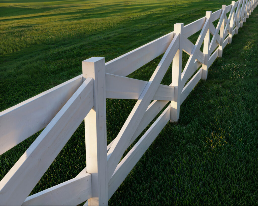 DIY crossbuck wooden fence surrounding a green pasture