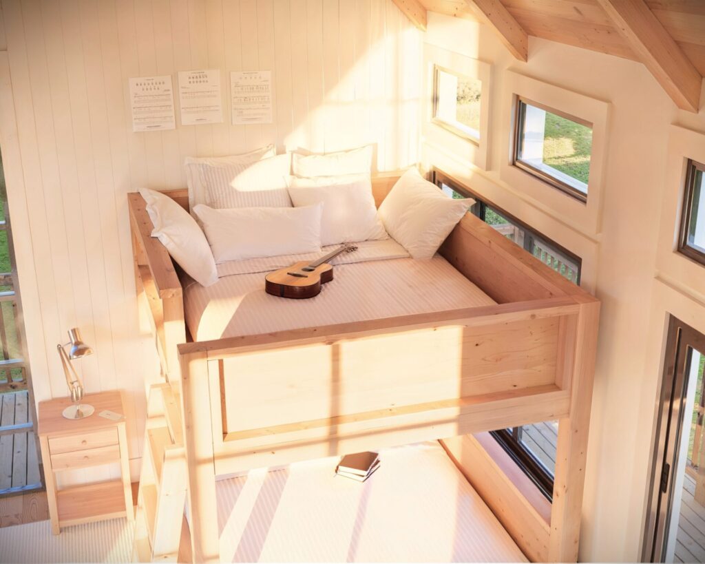Spacious and well-lit room featuring a full over full wooden bunk bed with a simple, sturdy ladder.