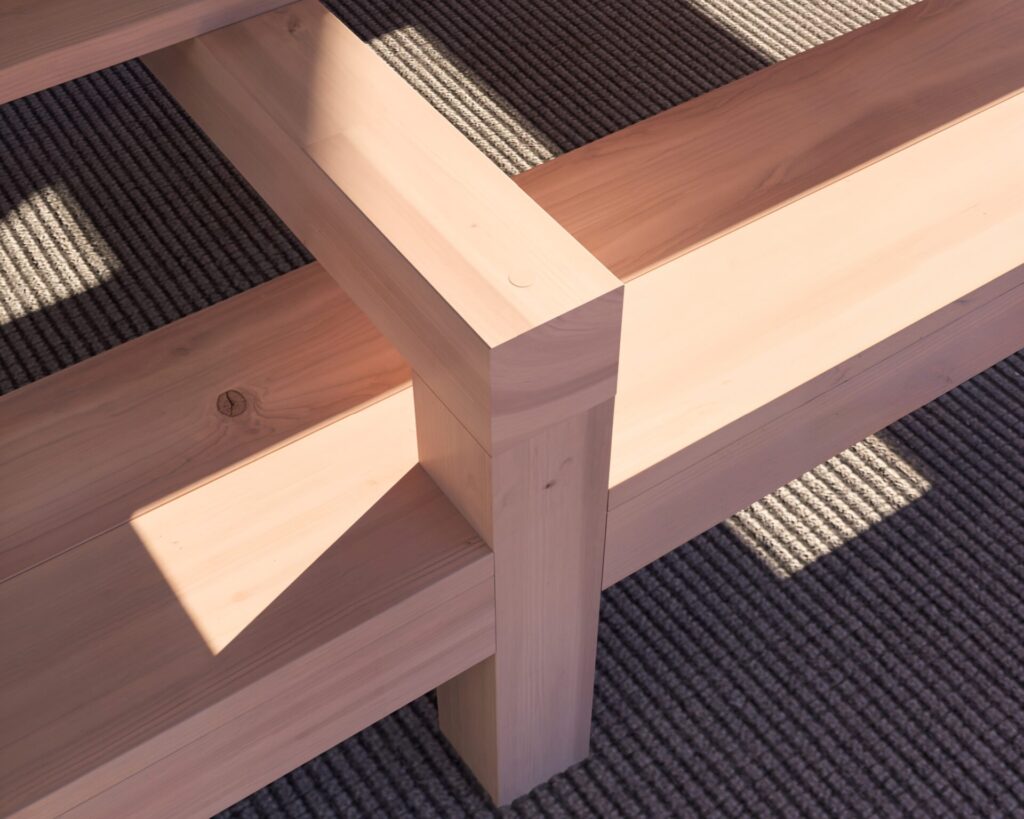 DIY wooden outdoor dining table with benches in a beautiful coastal setting, showcasing natural unfinished wood and robust construction.