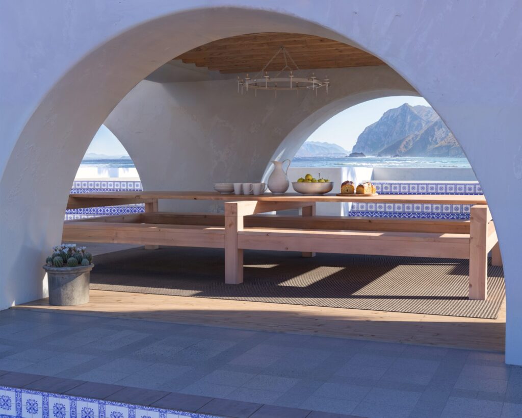 DIY wooden outdoor dining table with benches in a beautiful coastal setting, showcasing natural unfinished wood and robust construction.