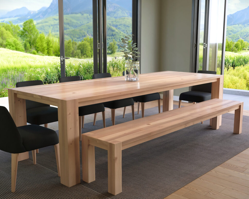 A modern farmhouse wooden dining table and bench set in a room with large glass doors showcasing a scenic outdoor view.