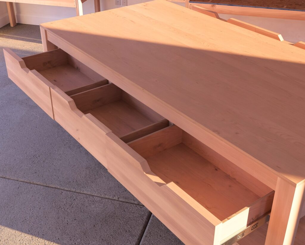 Custom-built DIY garage workbench with drawers and lumber storage in a well-organized garage.