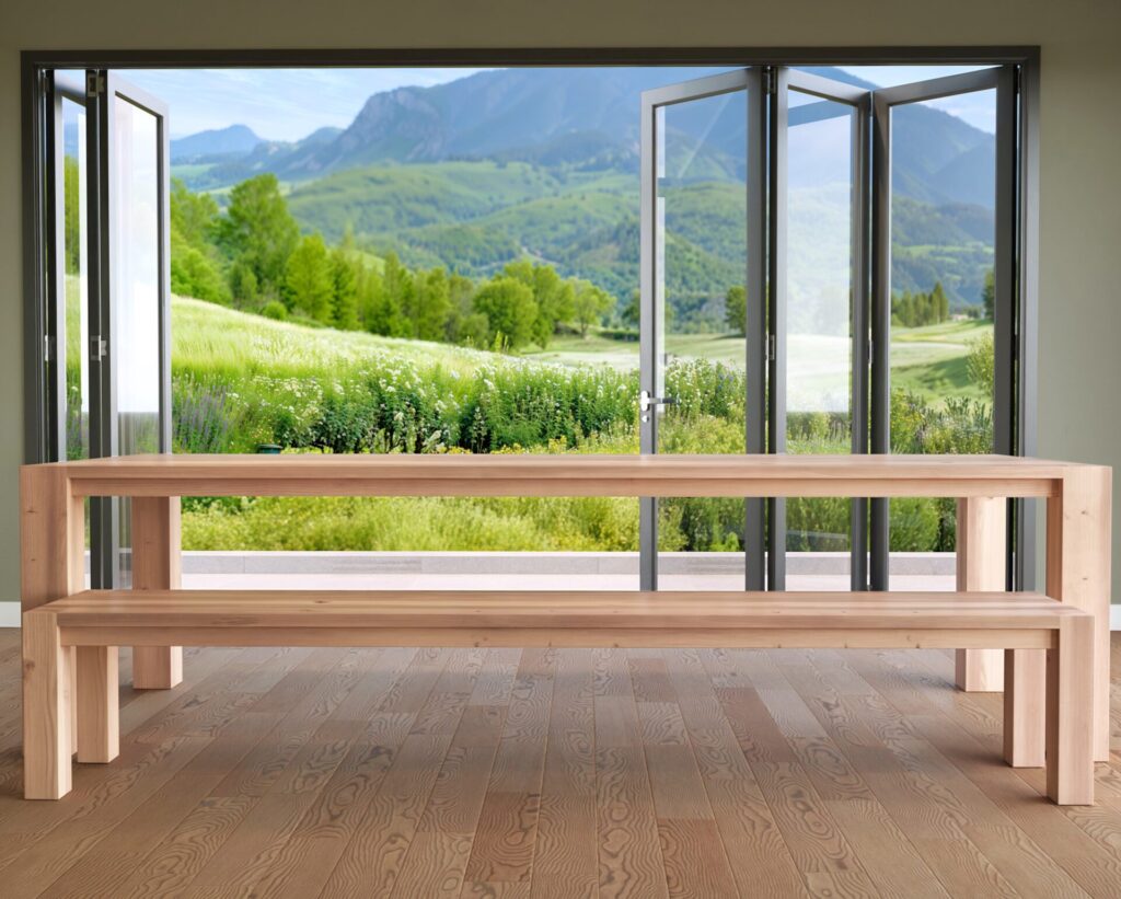 Rear view of the wooden dining table and bench set with large glass doors and a picturesque outdoor view.