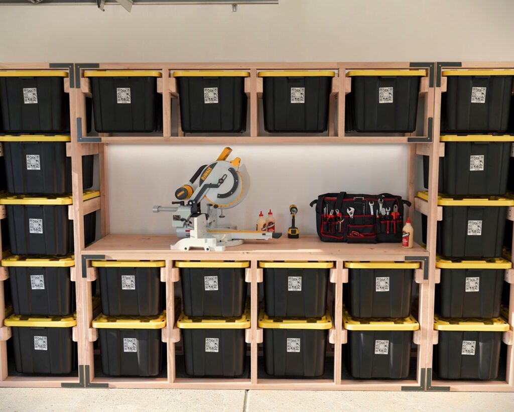 DIY 27-Gallon Tote Storage Rack in a garage, holding multiple black and yellow HDX storage totes, with a workbench integrated into the rack and a person scanning a tote using a QR code.