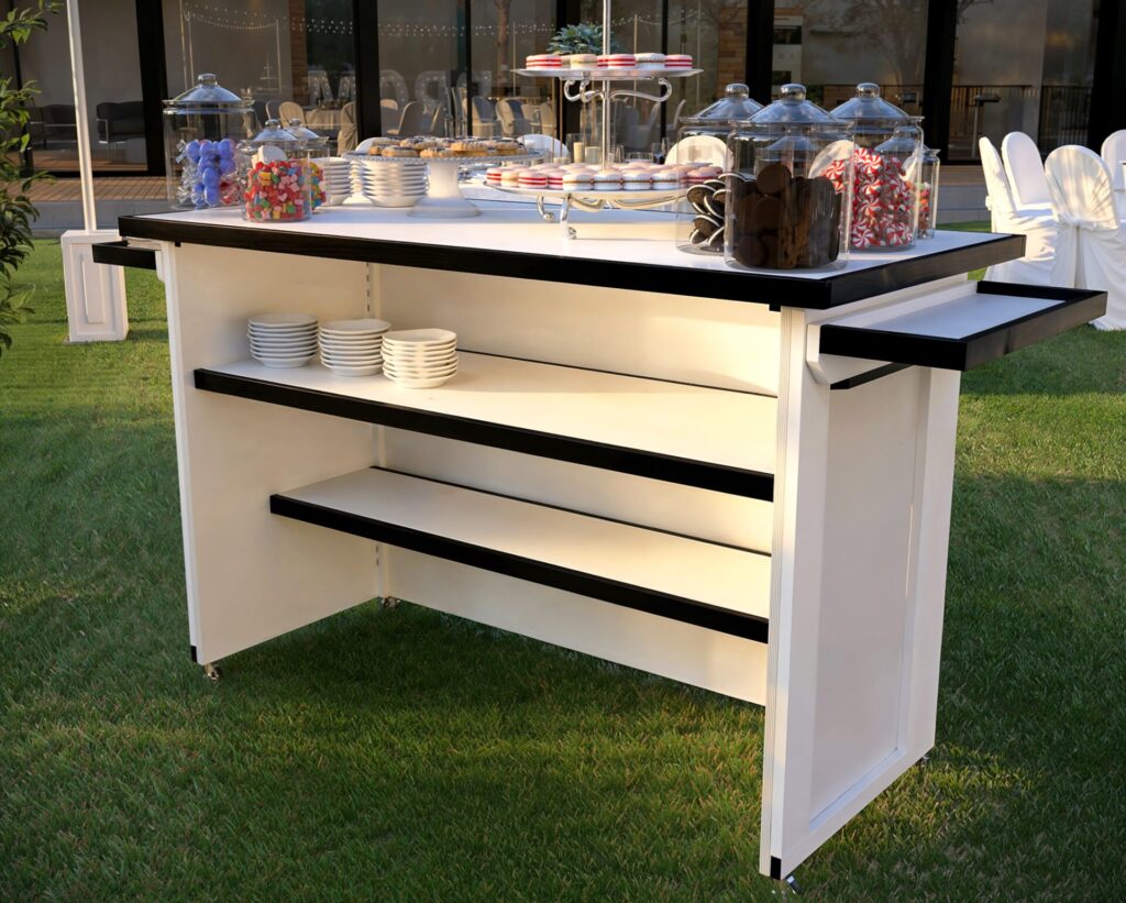 Elegant outdoor prom event with a folding event bar displaying desserts, surrounded by beautifully decorated tables, illuminated ‘PROM’ letters, and scenic mountain views.