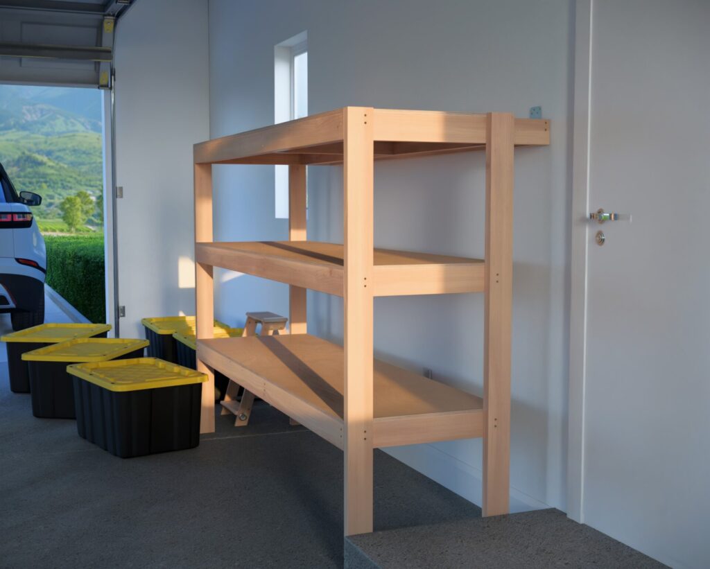 DIY garage shelving unit built with 2x4 lumber and plywood, designed to hold 27-gallon storage totes efficiently. The shelving features customizable configurations, making it a beginner-friendly and cost-effective storage solution for garages.